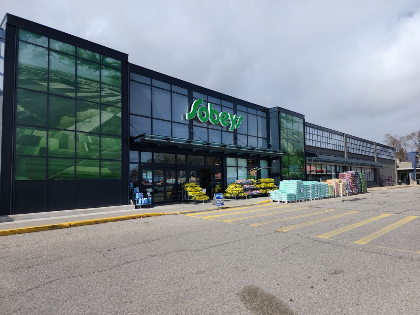 Retail plaza elevation with straight parapet coping, canopy fascia, and curtain-wall grid